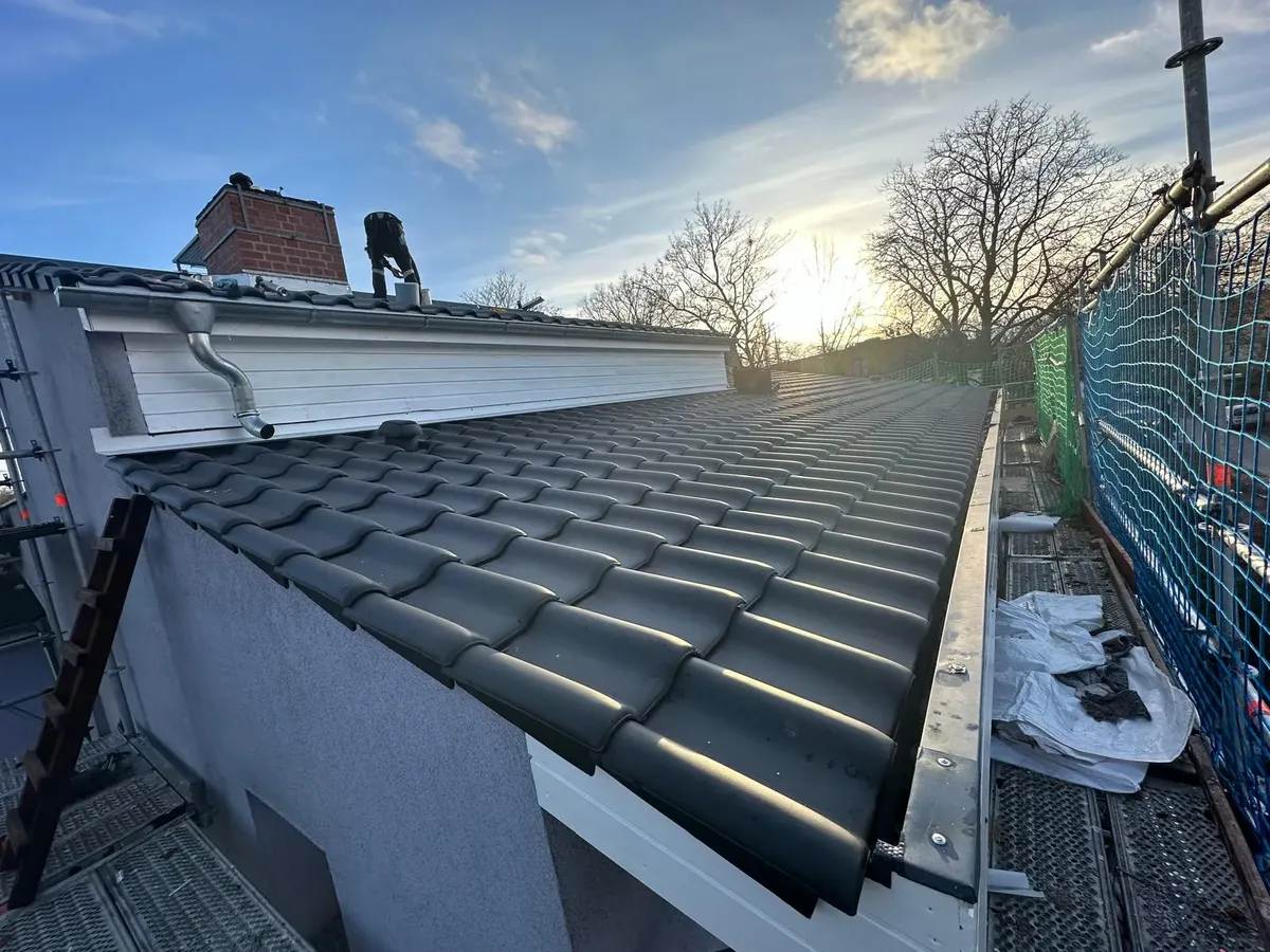 Beschädigte Firstziegel vor der Reparatur im Abendlicht
