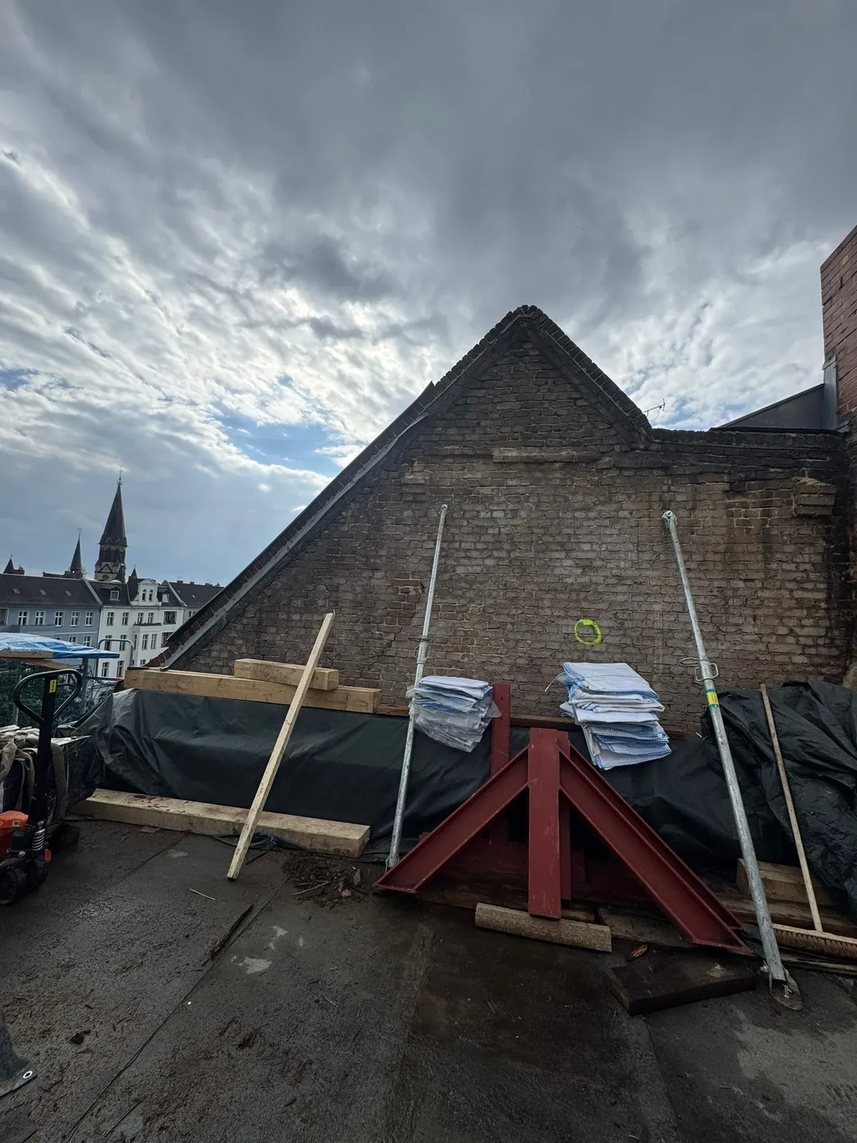 Kontrolle des Giebels an einem Altbau mit Berliner Kirchturm im Hintergrund