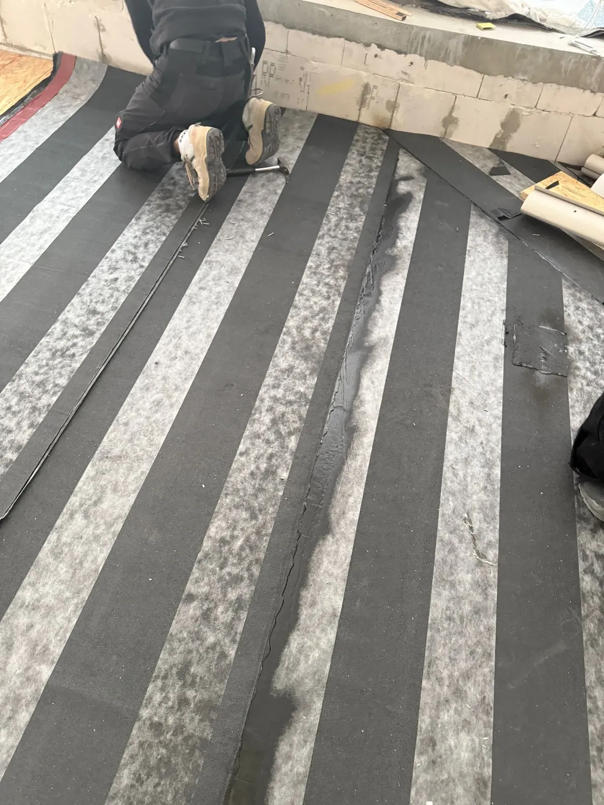 Kontrolle der Dämmbahnverlegung durch einen Arbeiter