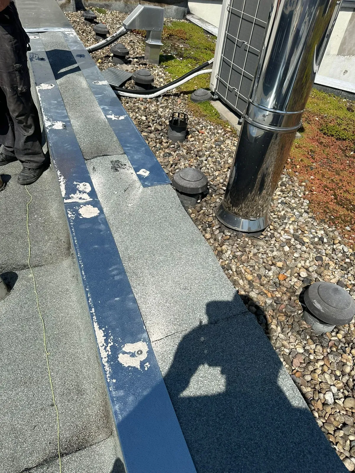 Wartungskontrolle an der Attika neben Schacht und Solarmodul
