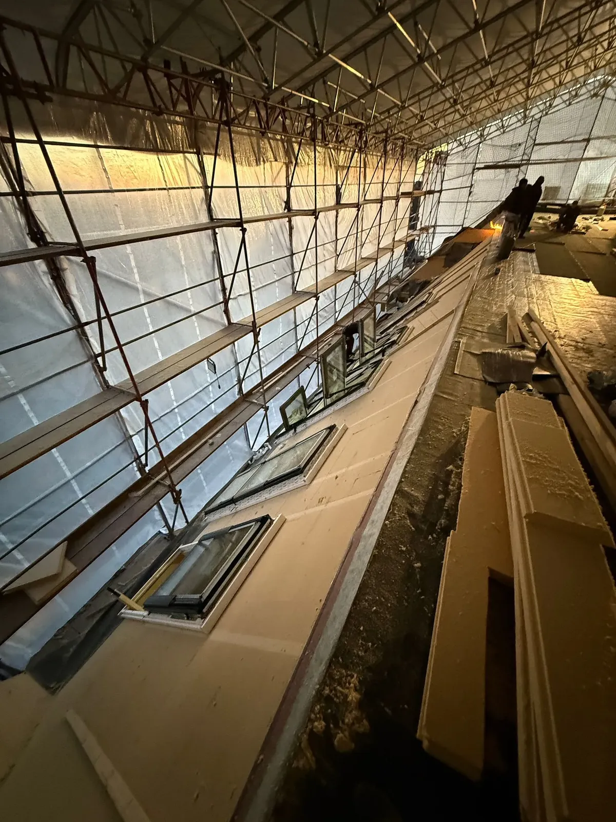 Reihe neu montierter Dachflächenfenster unter einem Wetterschutzzelt bei der Neueindeckung