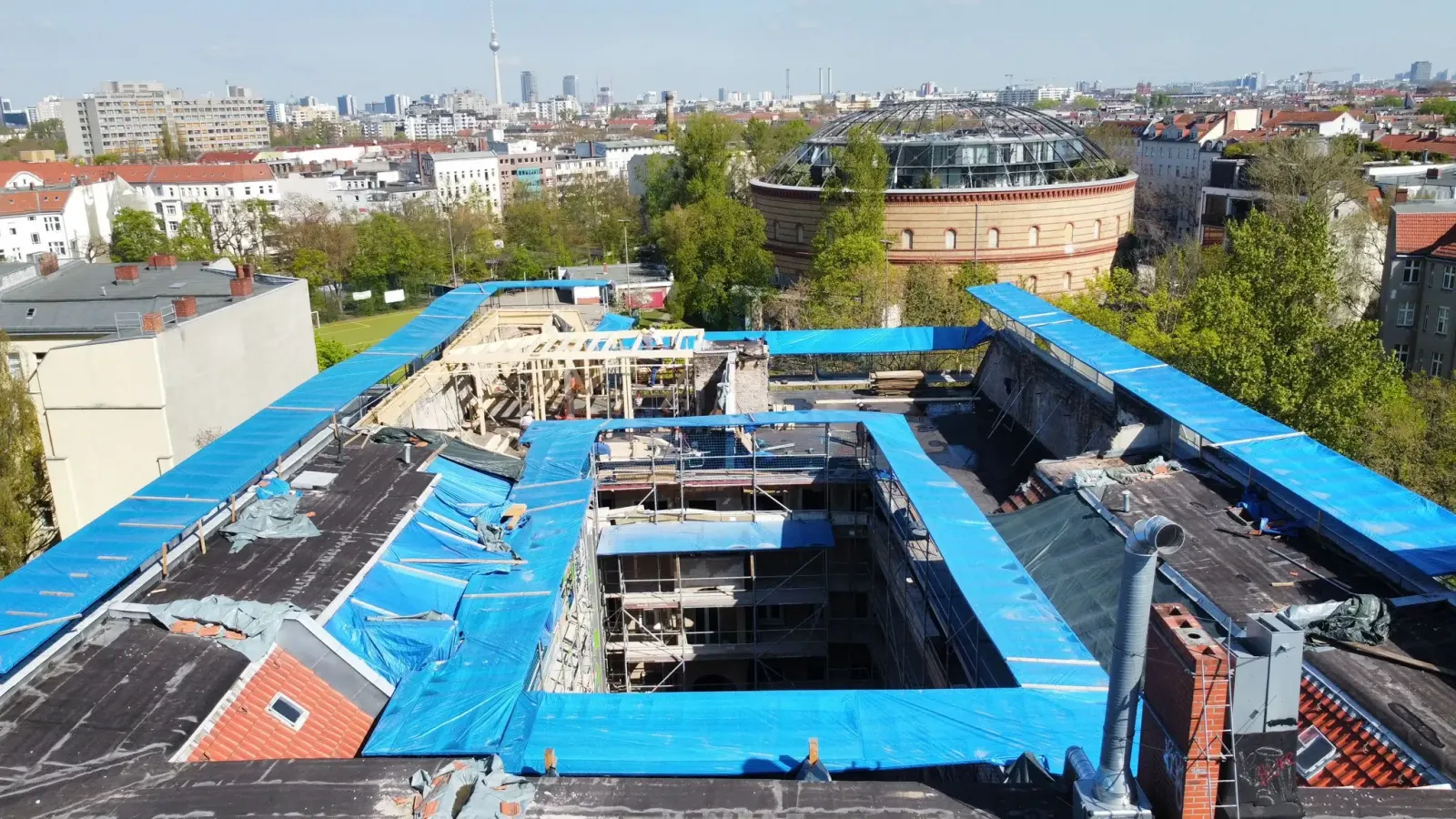 Drohnenaufnahme eines neuen Dachstuhls mit Fernsehturm und historischem Rundbau im Hintergrund, Berlin