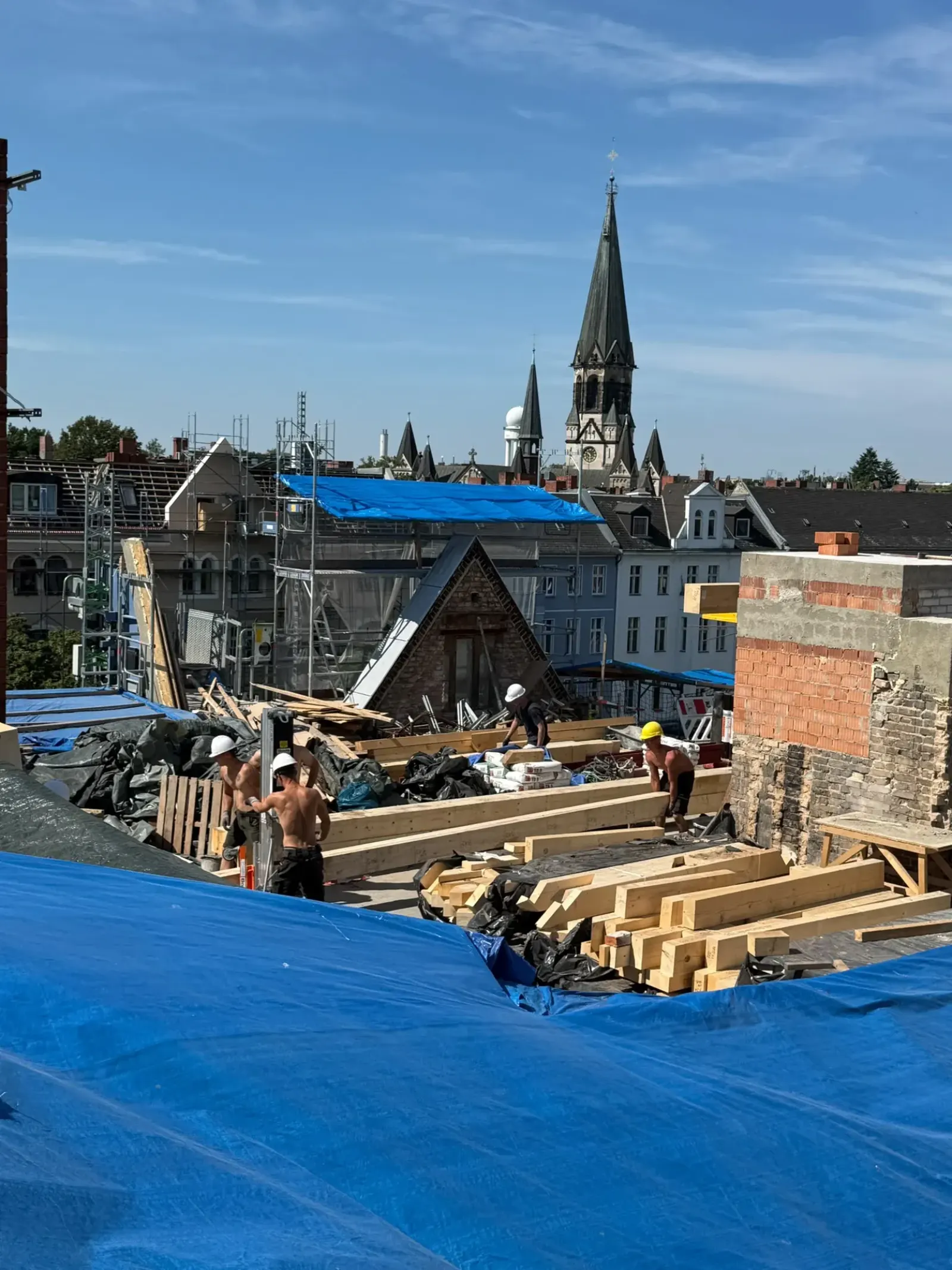 Vier Zimmerer montieren einen neuen Dachstuhl, Berliner Kirchturm im Hintergrund
