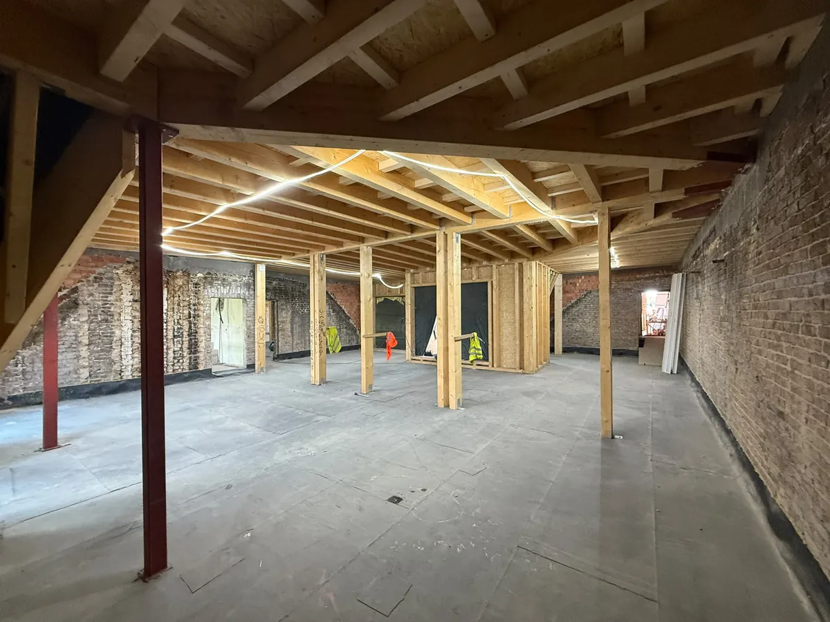 Innenansicht der Gewerbehalle mit fertiger Holzkonstruktion und beleuchtetem Innenraum