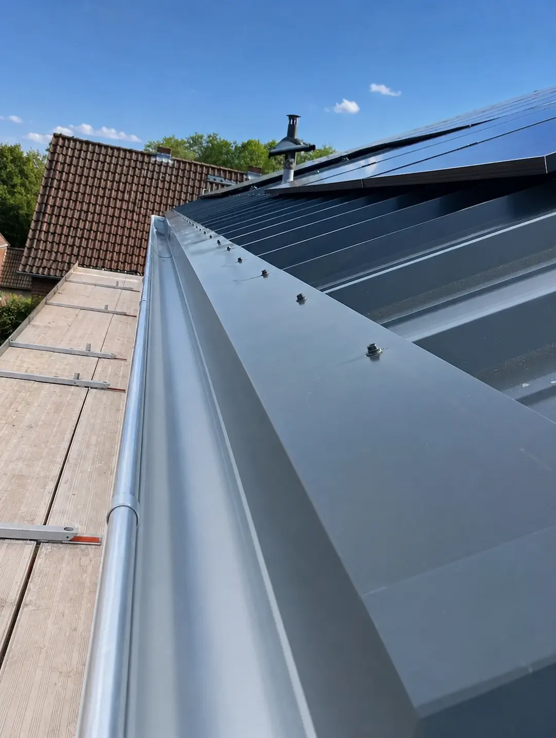 Neuer Dachrinnenanschluss an einem modernen Metalldach mit sauber ausgeführter Blechverarbeitung.